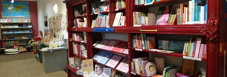Bücherregal mit Büchern und Geschenken zur Geburt und Taufe.