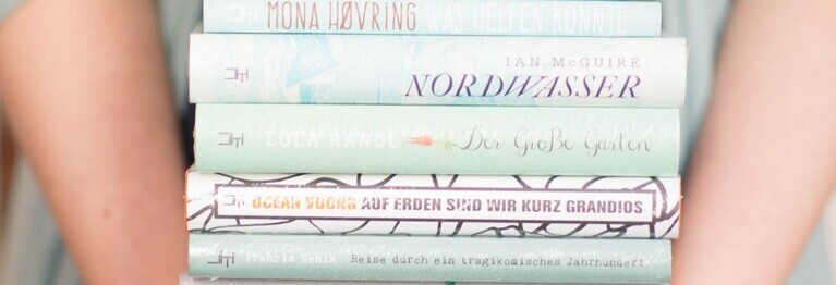 Zwei Arme halten einen Bücherstapel