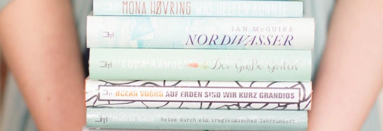 Zwei Arme halten einen Bücherstapel