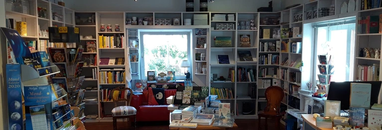 Blick in den hinteren Raum der Buchhandlung mit den diversen Abteilungen und einem rotem Sofa vor dem Fenster